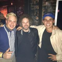 Three young men smiling together at a night-time venue