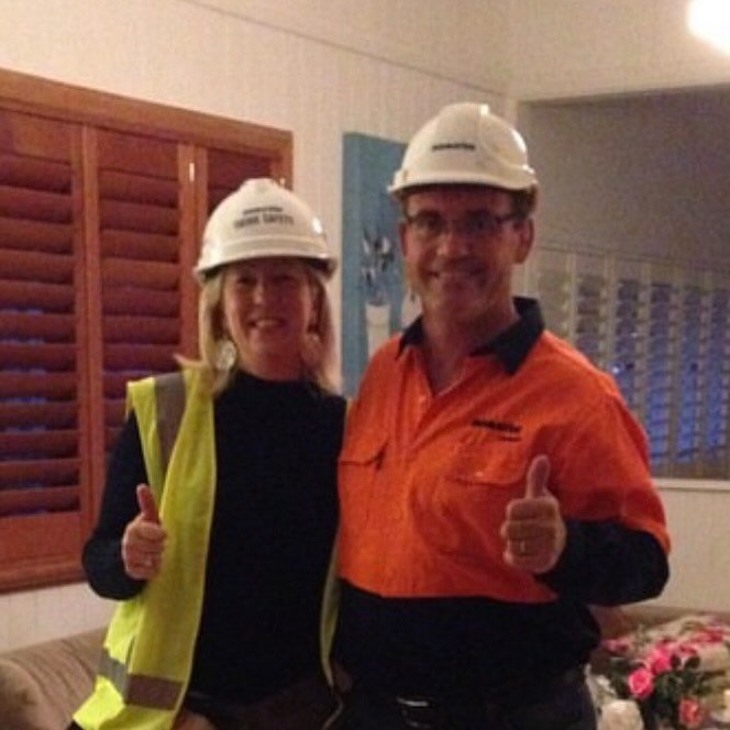 Man and woman in hard hats and work gear giving a thumbs up
